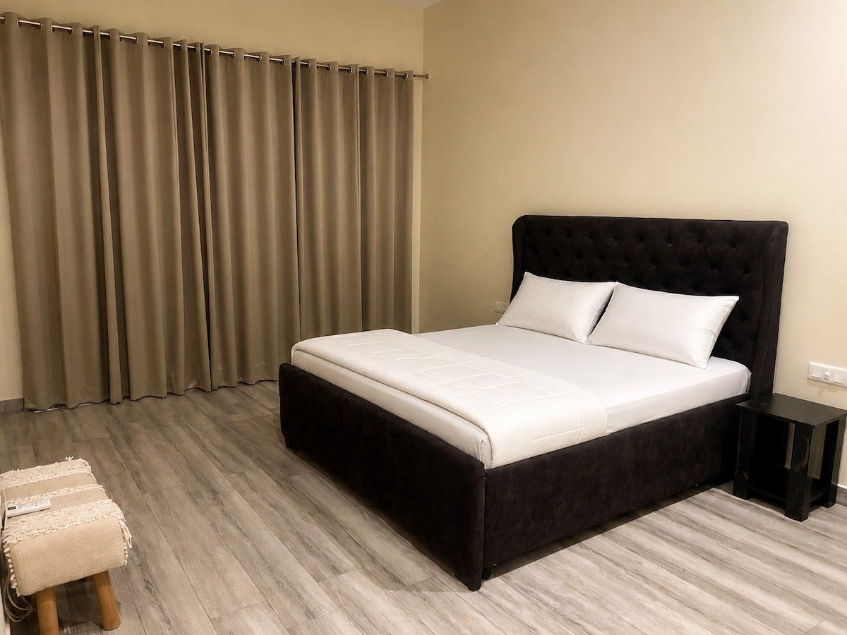 Bedroom with a dark upholstered double bed and white linen